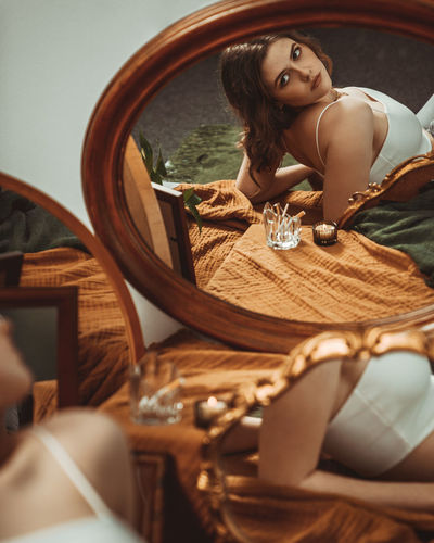 Beautiful young woman lying infront of different mirrors.