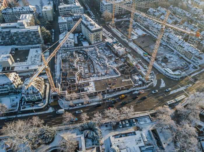 Aerial view of cranes and buildings in city during winter