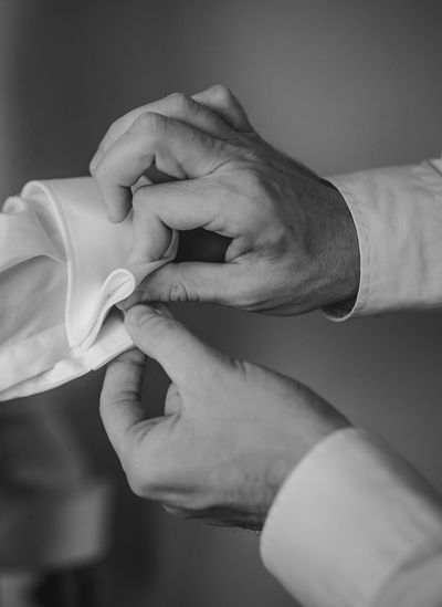 Cropped photo of male hands fasten the button on formal shirt