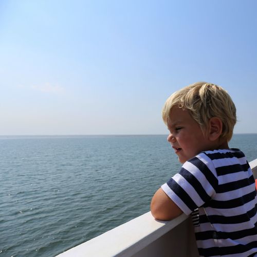 Side view of boy looking at sea against clear sky