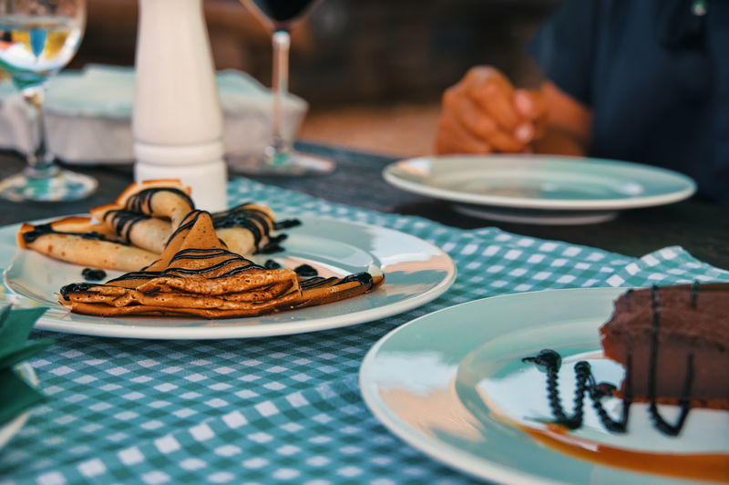 Midsection of woman sitting at the table with cake and pancakes on it