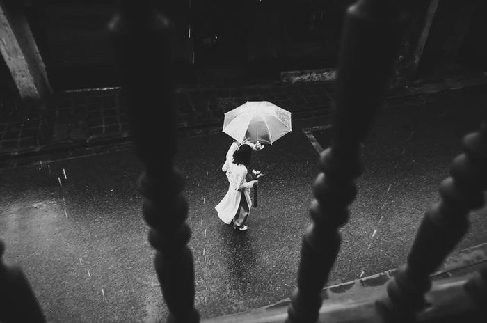 High angle view of man and woman in umbrella walking on street in rainy season