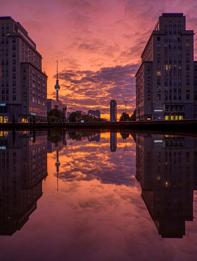 Reflection of buildings in lake against sky at sunset