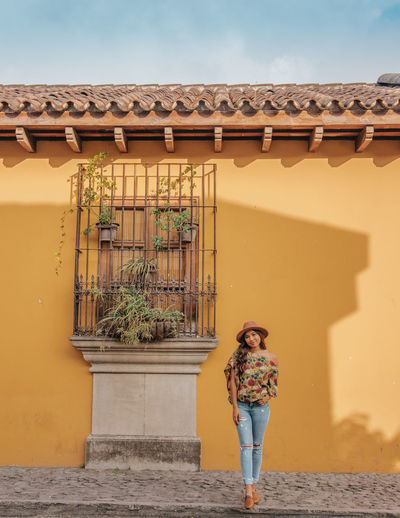 Portrait of woman standing against house