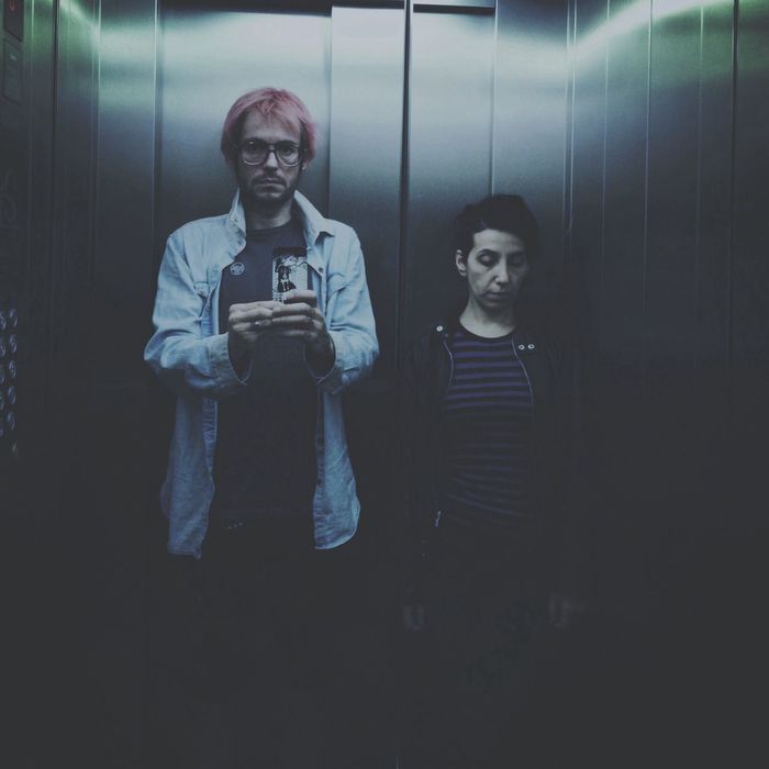 Reflection of man with friend photographing in elevator on mirror