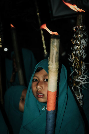 Portrait of girl with flaming torch at night