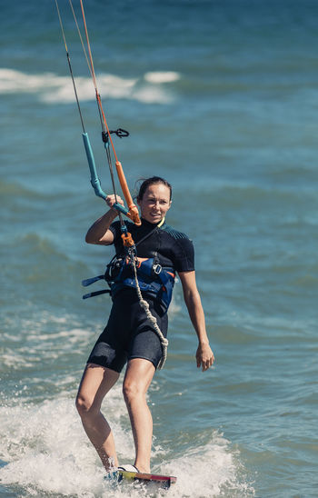 Smiling woman kiteboarding in sea