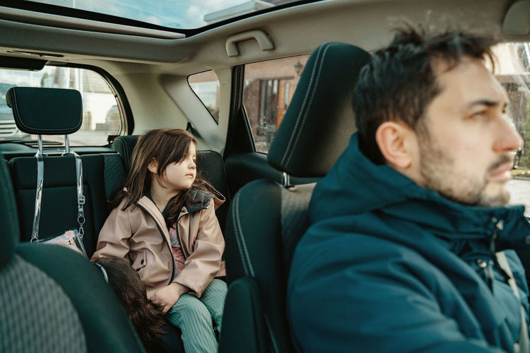 Portrait of daughter and father sitting  in car