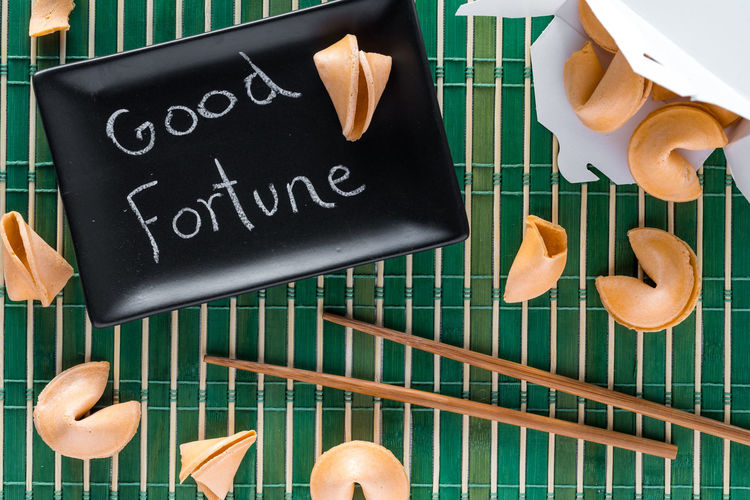 Fortune cookies on a bamboo mat with chopsticks and a note on a sushi plate.