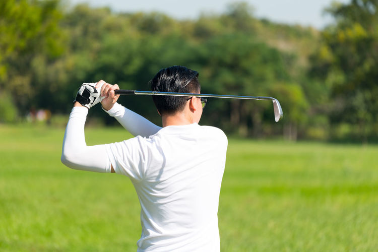 Rear view of man playing at golf course