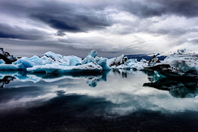 Scenic view of icebergs against dramatic sky