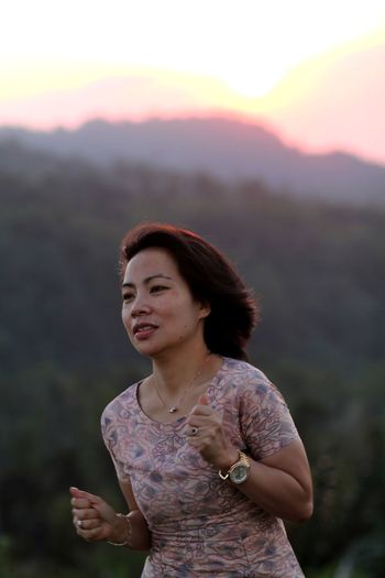 Woman looking away against mountains during sunset