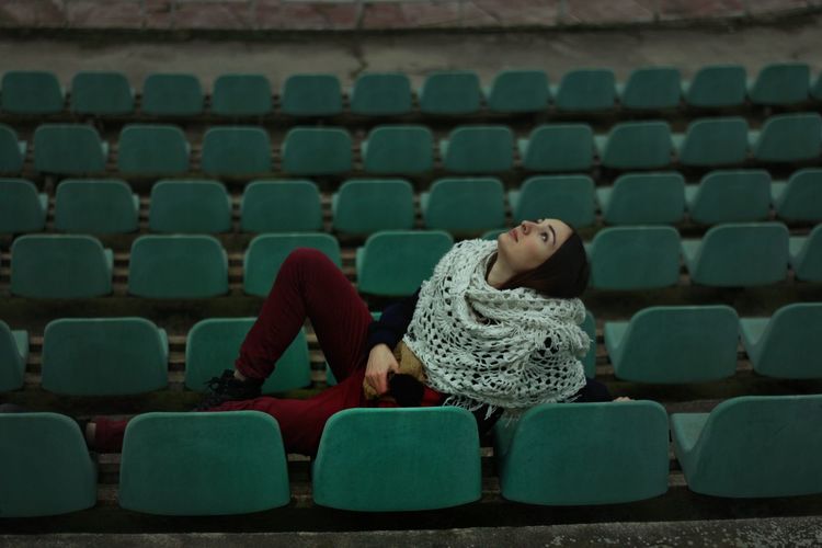 Woman reclining on chairs at stadium