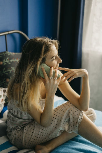 Young beautiful woman laughs and speaks by phone freelancer