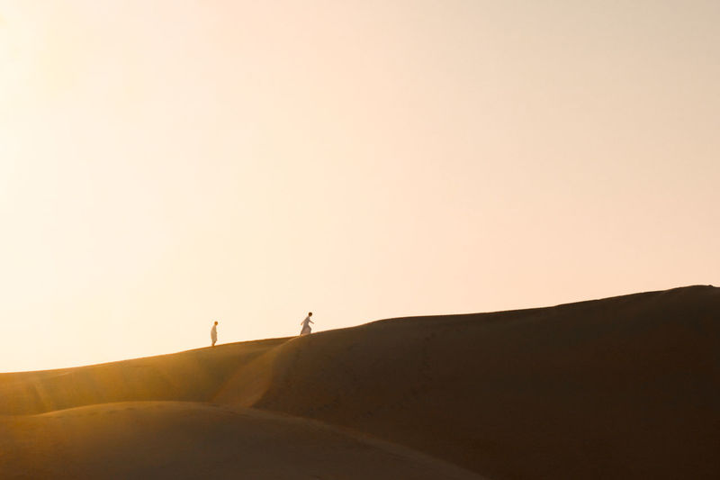 Silhouette person standing on desert against clear sky
