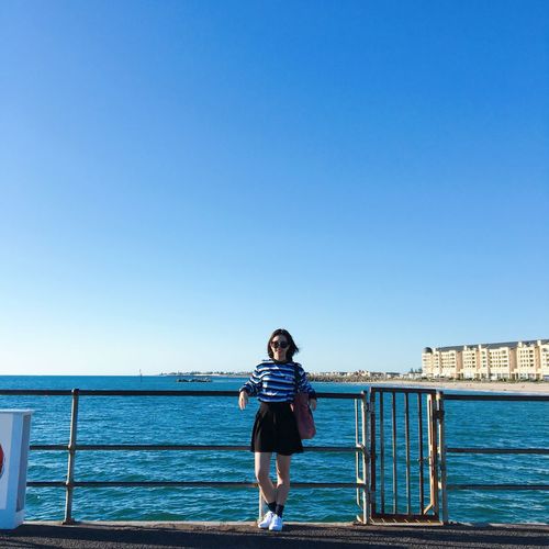 Full length of woman standing against sea and blue sky