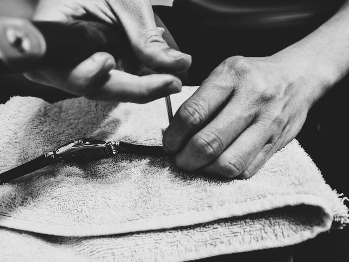 Cropped hands of man repairing wristwatch on table at home