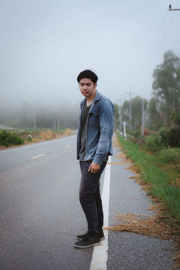 Full length portrait of young man standing on road