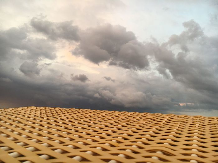 Low angle view of roof and building against cloudy sky