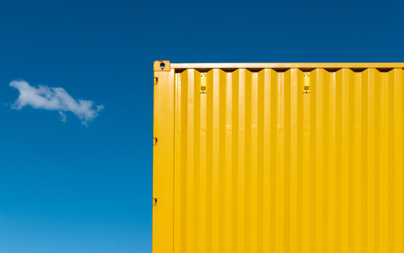 Low angle view of yellow wall against blue sky