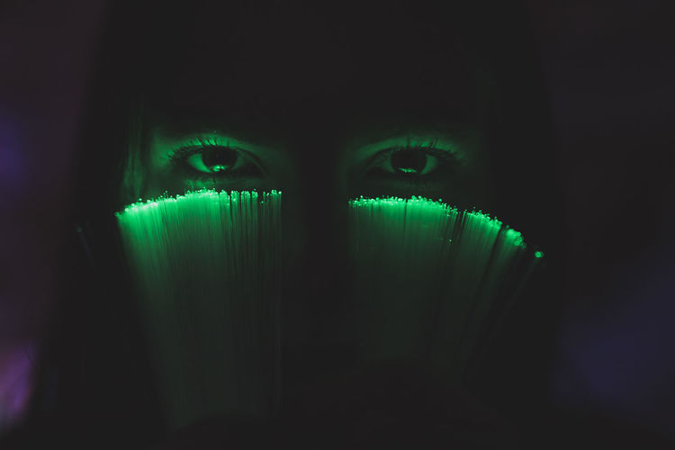 Close-up portrait of young woman holding illuminated fiber optic