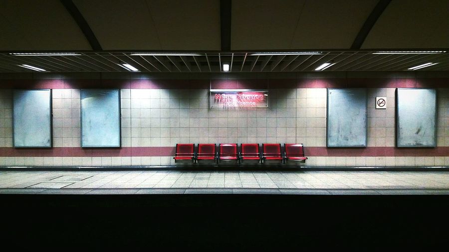 Empty chairs against illuminated wall at subway station