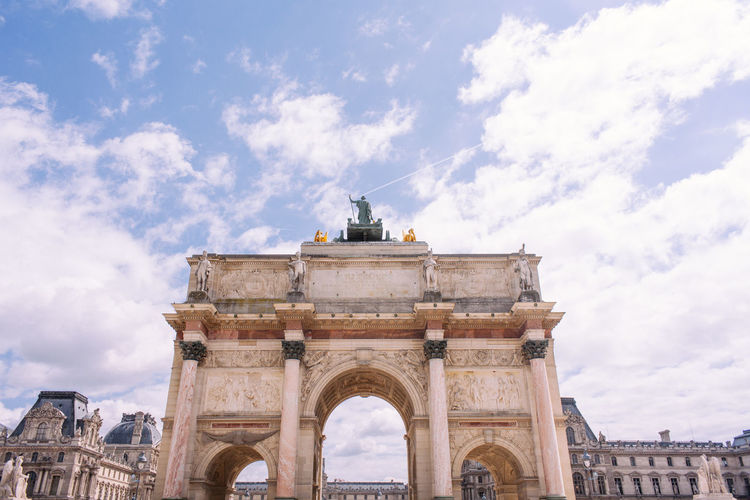 Low angle view of triumphal arch against cloudy sky