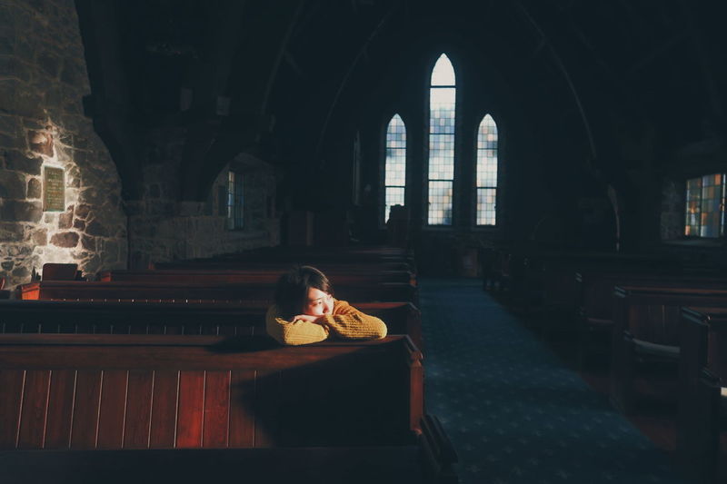 Young woman sitting in dark christian church