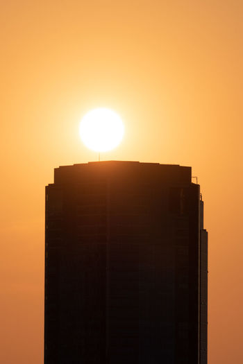 Low angle view of silhouette building against orange sky