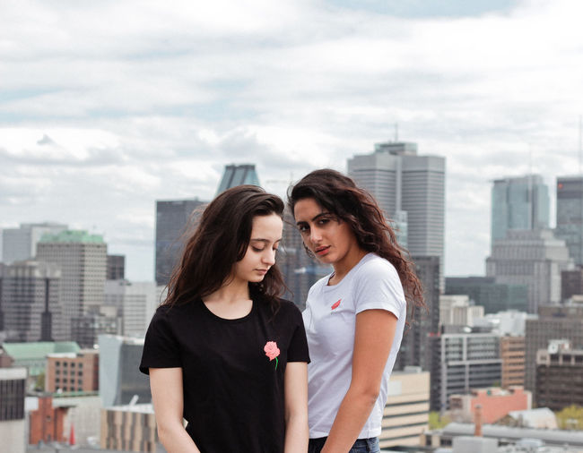 Young women standing against modern cityscape