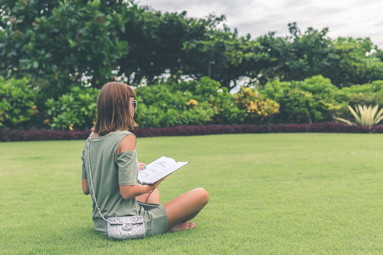 Girl on the lawn in the park reads a book