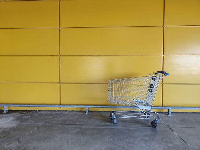 Shopping cart on yellow wall