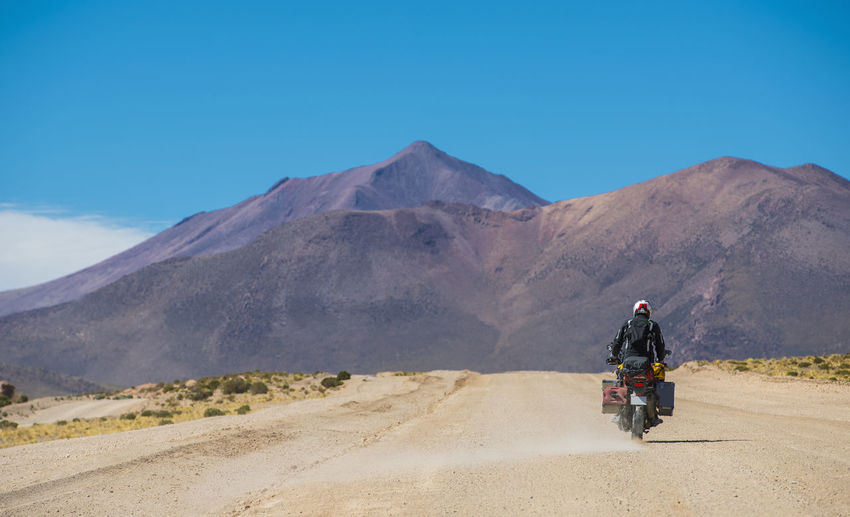 Man riding touring motorcycle on dusty road in bolivia