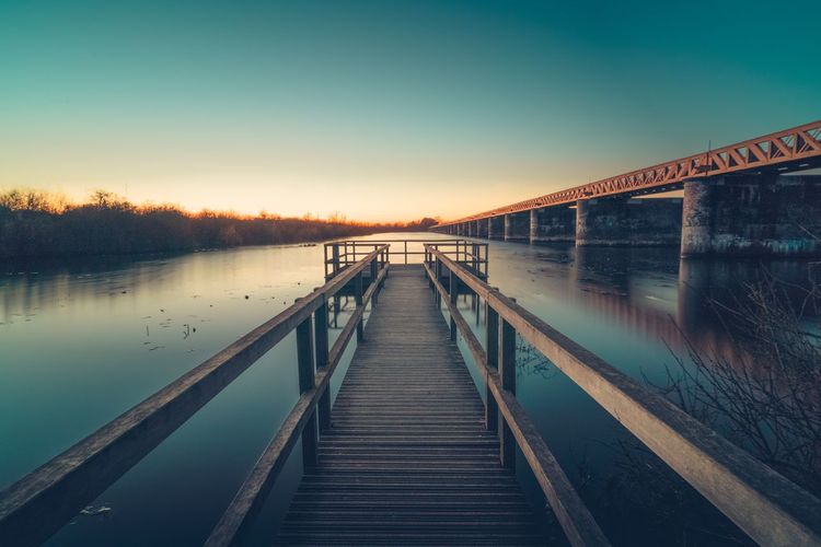 Pier over lake against clear sky