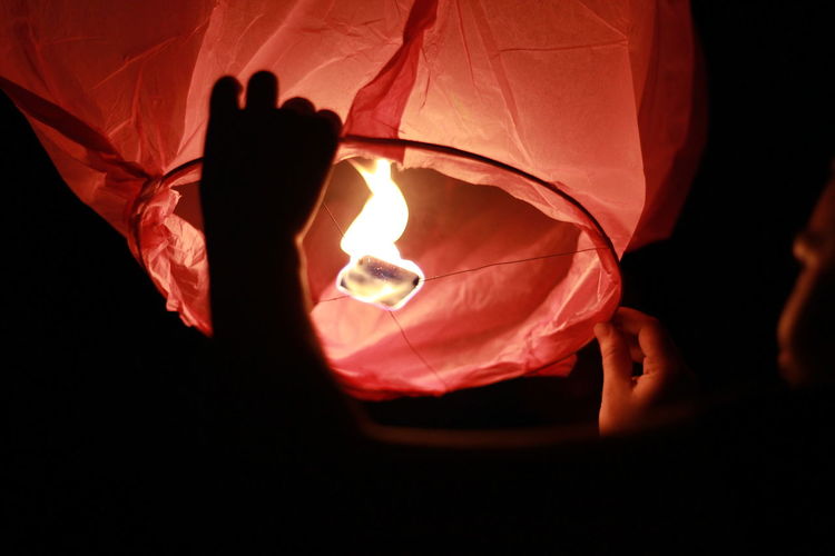 Cropped image of person holding paper lantern at night