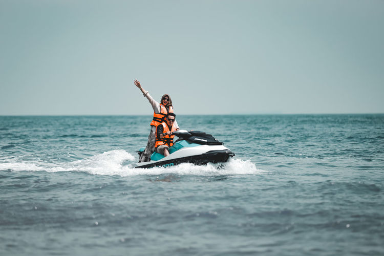 People in boat on sea against sky