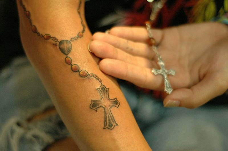 Cropped hand showing tattoo and cross