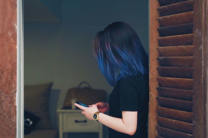 Side view of woman using phone at home