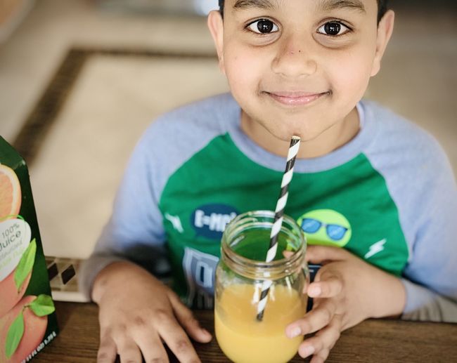 Portrait of cute boy drinking glass on table