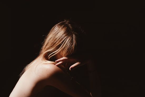 Naked woman with long blond hair sitting in darkroom