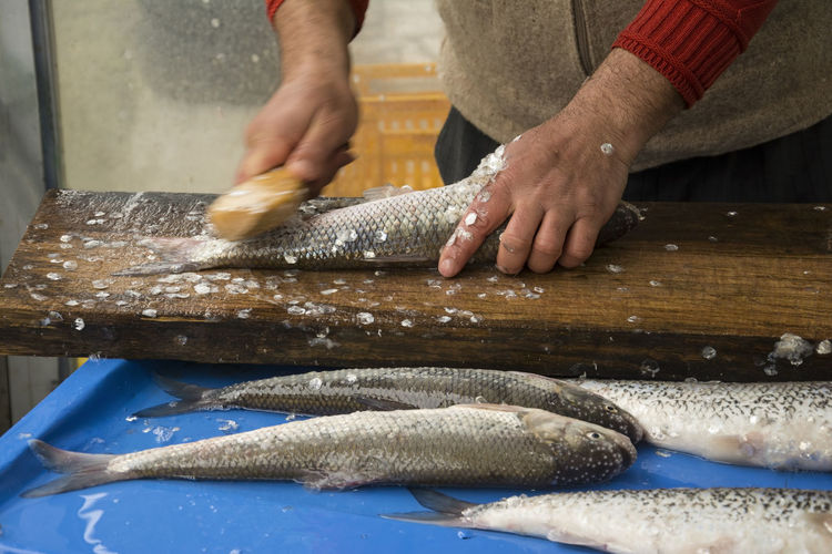 A fisherman removing the fish scales by hand