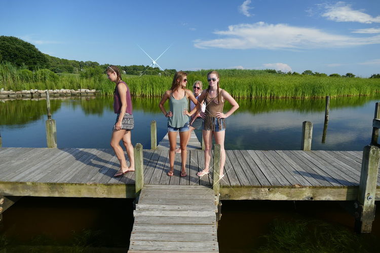 People standing on pier over lake against sky