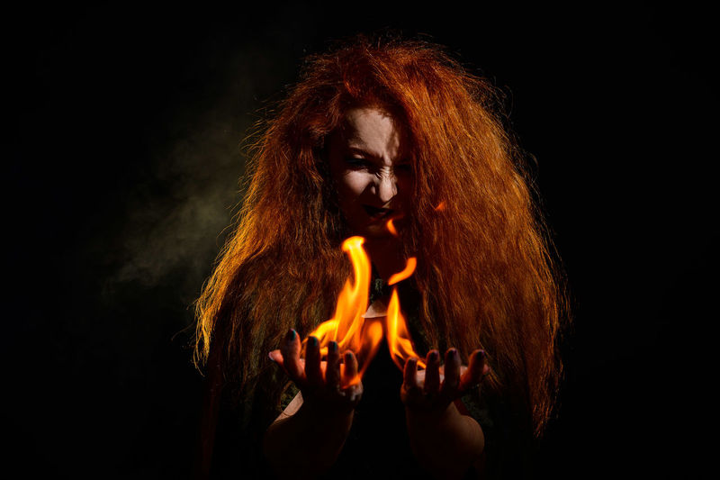 Portrait of woman with fire crackers against black background