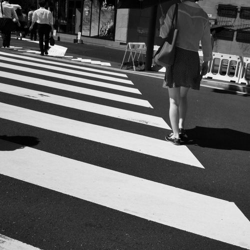 Low section of woman crossing road