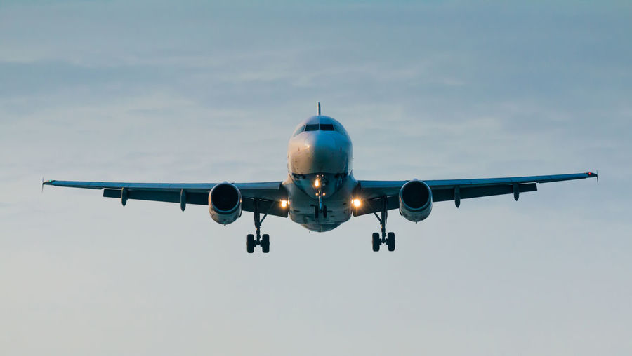Low angle view of airplane flying against cloudy sky