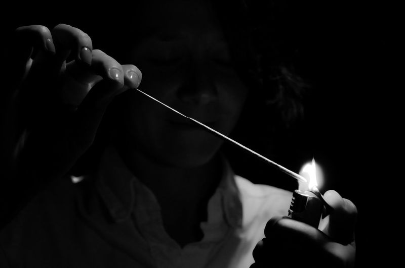 Cropped hands burning sparkler with cigarette lighter