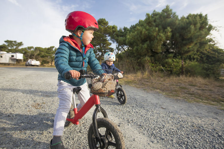 Brother and sister biking on gravel road.