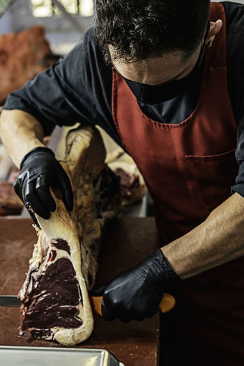 Professional butcher with mask preparing and cutting meat
