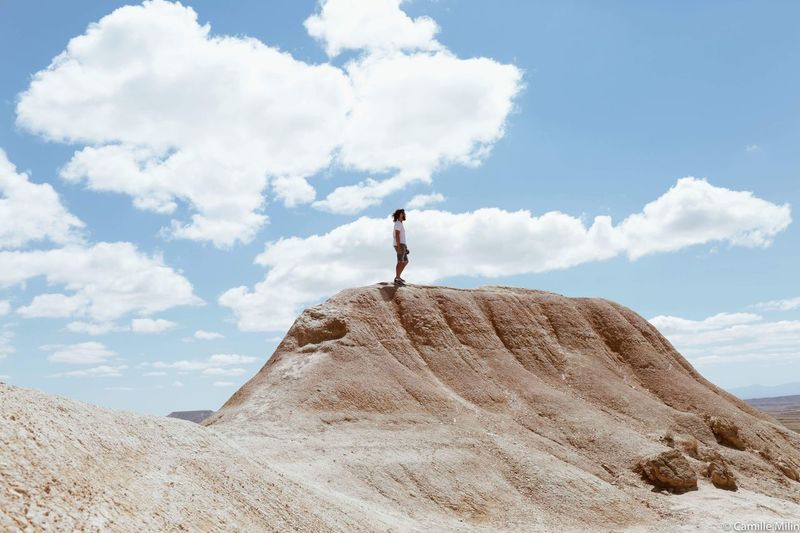 Man standing on rock formation against sky