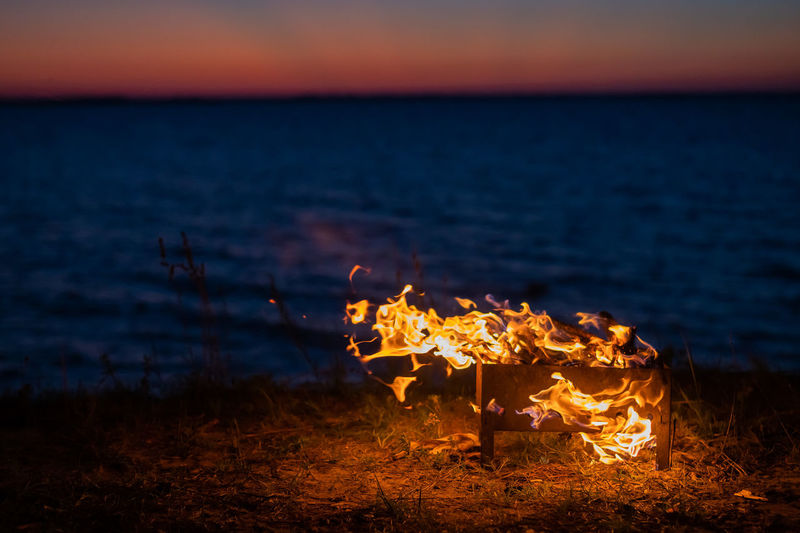 Bonfire on beach against sky during sunset
